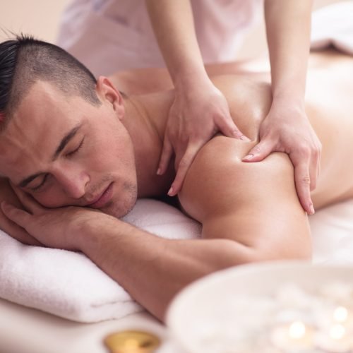 Positive young man having a back massage in a spa center